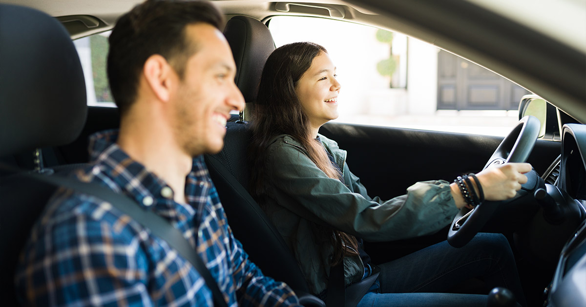 Young woman driving Ford car with passenger, both smiling, city background, comfortable interior