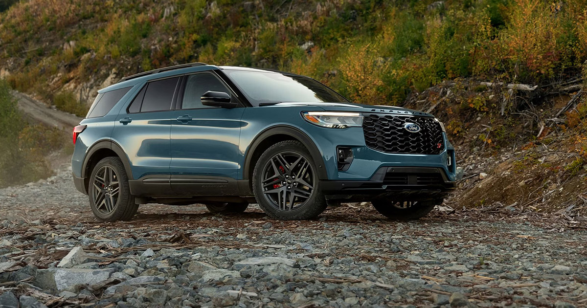 Blue Ford Explorer SUV on rocky terrain with autumn forest background, showcasing rugged off-road capability
