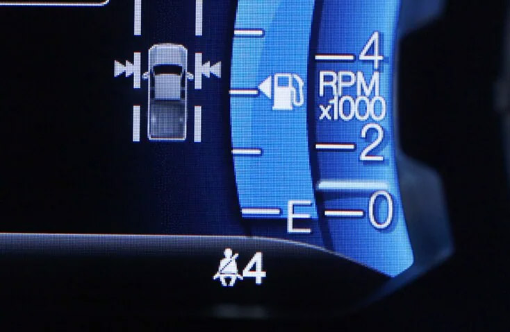 Car dashboard display showing fuel gauge, RPM meter at 2000, and seatbelt reminder icon, typical of modern Ford vehicle instrument cluster