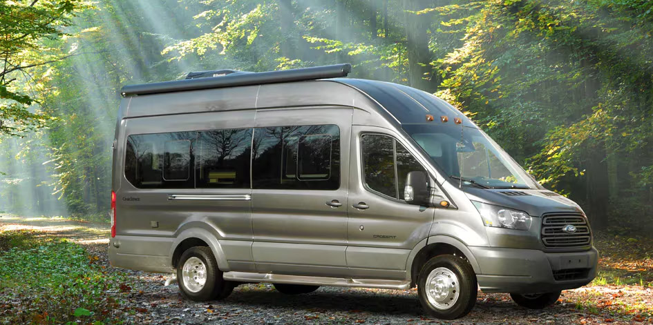 Ford Transit passenger van parked in misty forest with sunlight streaming through trees, showcasing adventure and travel potential