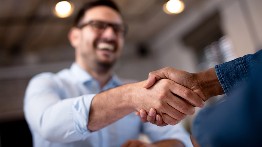 Business professionals shaking hands in an office setting, symbolizing partnership and agreement.