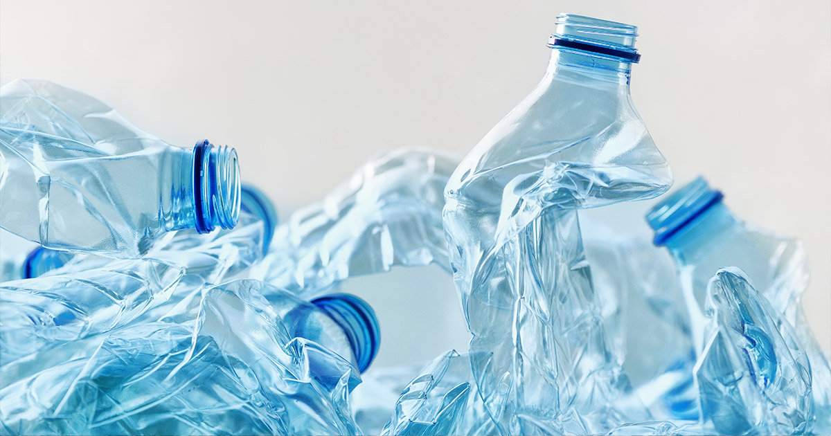 Crumpled clear plastic water bottles with blue caps, symbolizing recycling and environmental awareness